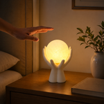 Veilleuse figurine en résine blanche, mains ouvertes autour d’une sphère lumineuse