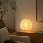 Lampe Wabi allumée sur table, abat-jour sphérique en fibres claires et trépied
