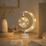 Veilleuse Séléné en forme de croissant, globe en verre lumineux sur socle blanc.