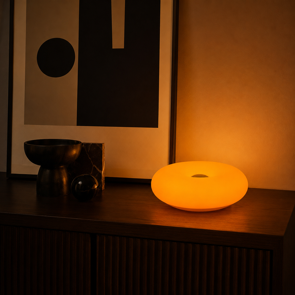 Lampe Halo ronde orange posée sur meuble, lumière diffuse et ouverture centrale
