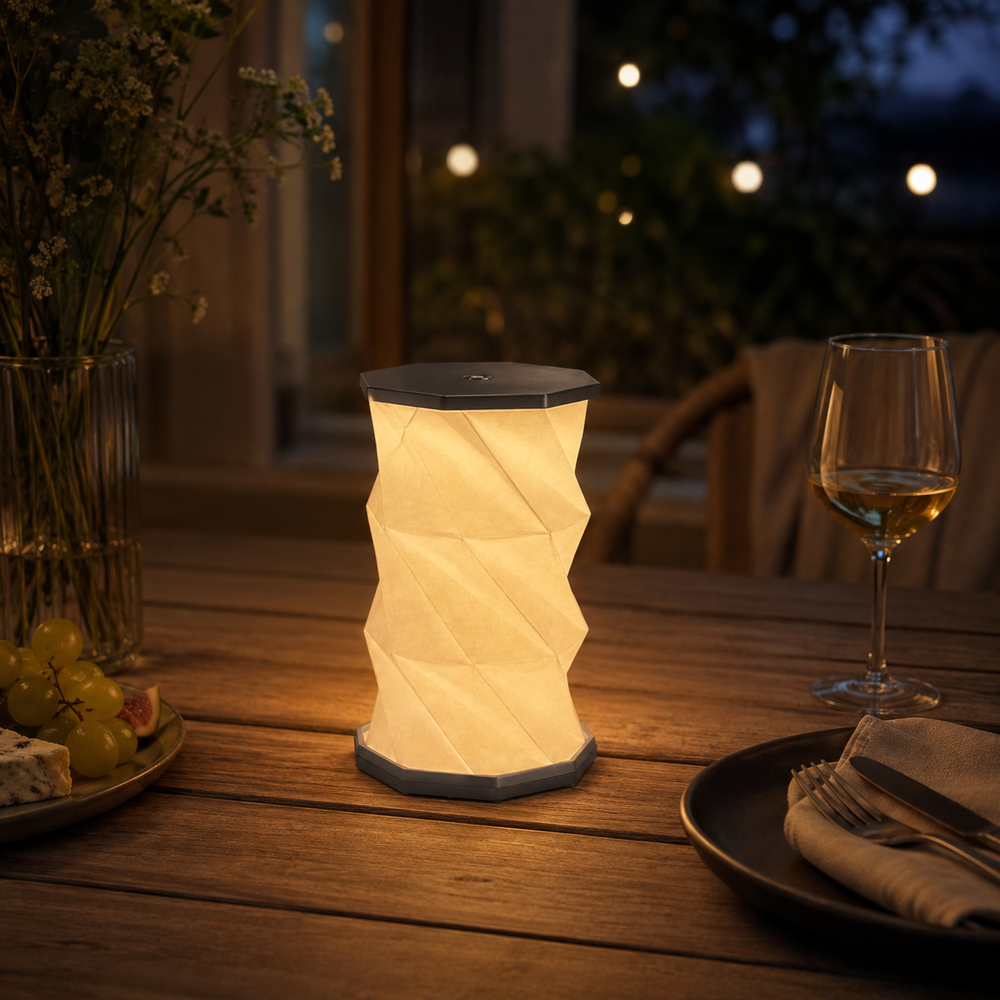 Lampe plissée nomade beige avec abat-jour plissé, base hexagonale grise et capot noir