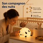 Veilleuse mouton lumineuse posée sur un meuble près d’un lit bébé
