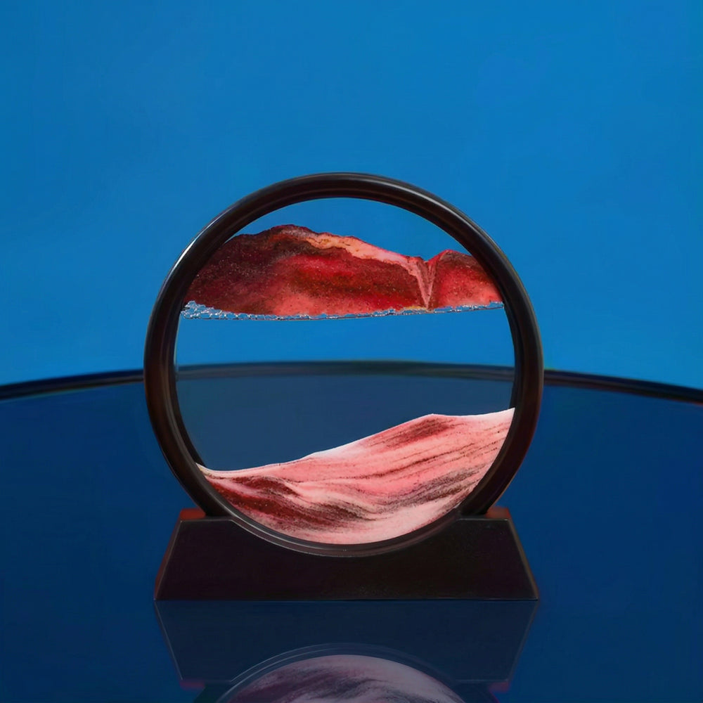Lampe sablier cinétique LED ronde, relief rouge et rose sur socle sombre.