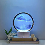 Lampe sablier cinétique LED ronde, relief bleu type montagnes sur socle blanc.